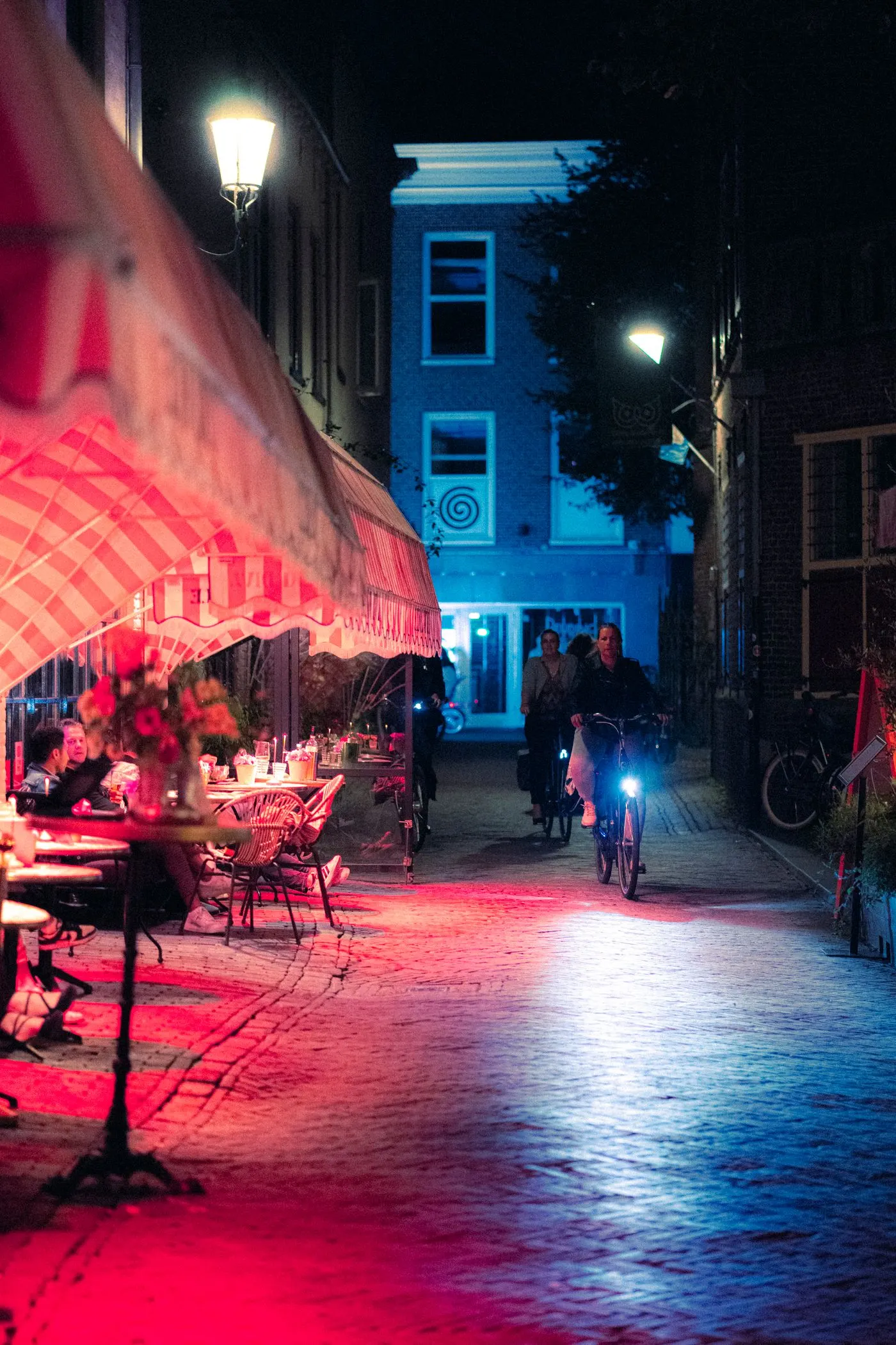Verlicht steegje in Amersfoort in de avond met fietsen en terrastafels