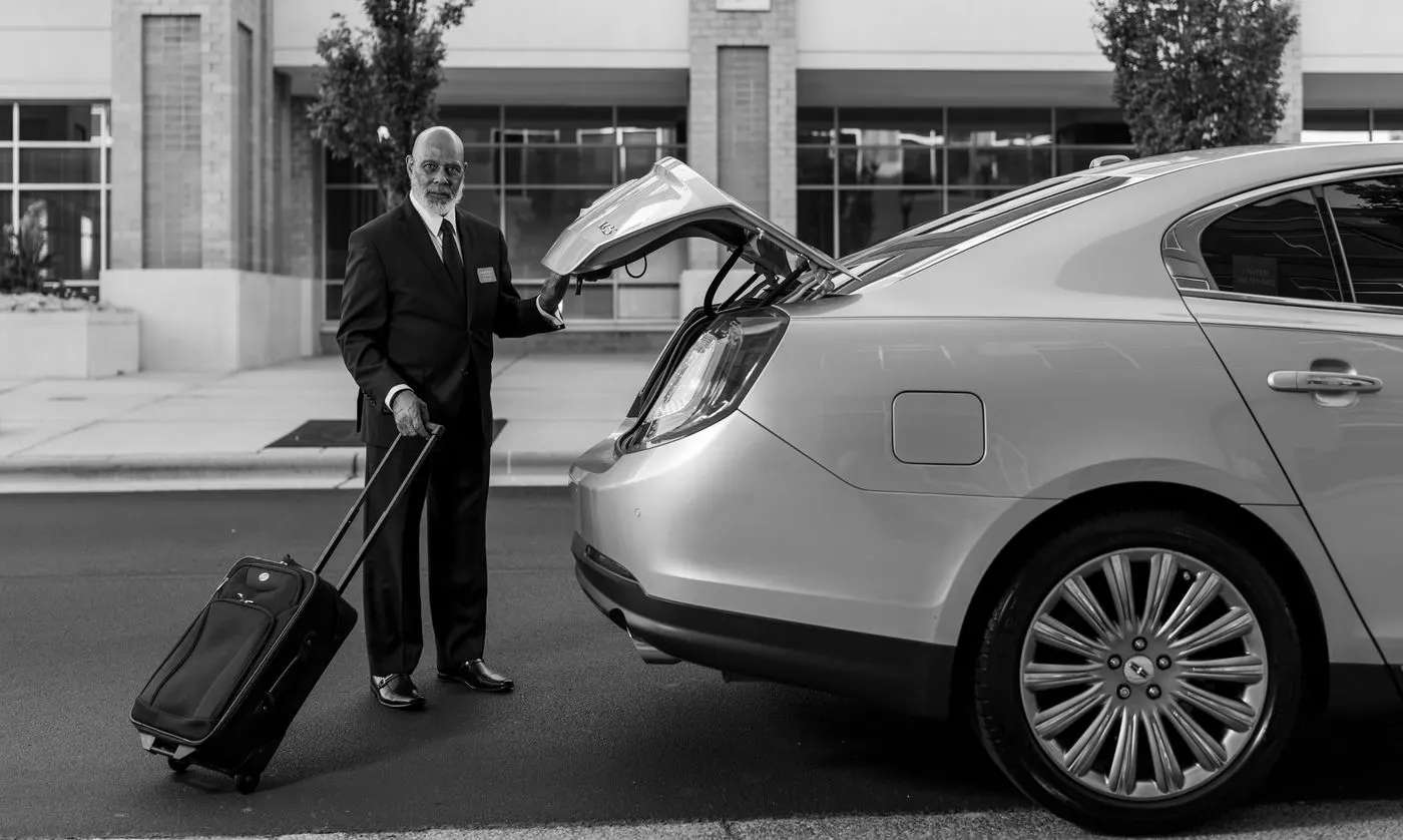 Chauffeur laadt koffers in de kofferbak van een taxi