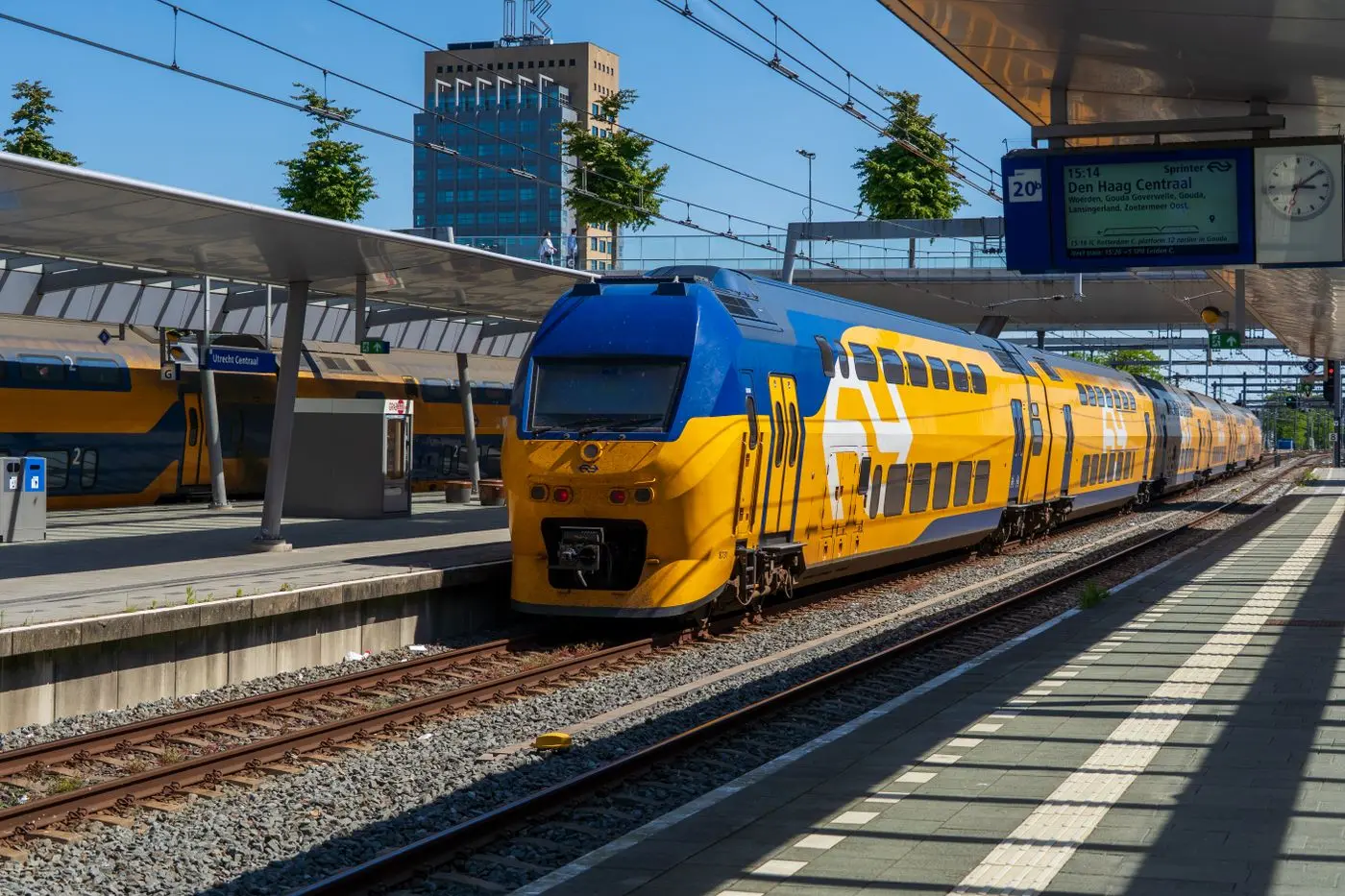 Blauw-gele intercity rijdt een Nederlands station binnen