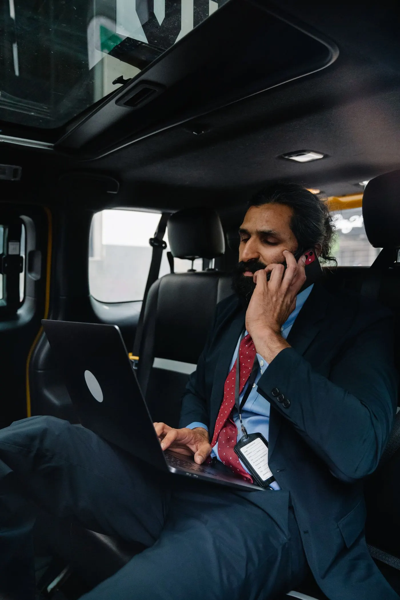 Zakenman werkt op zijn laptop op de achterbank van een taxi